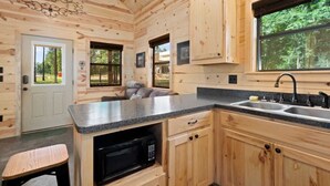 L’intérieur d’une cabane en bois comprend un espace cuisine avec un plan de travail, un évier et des placards.