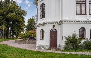 A white building with a dark brown door, arched windows, and a small porch with a bench. - Nice apartment in Tranås (Tranås)