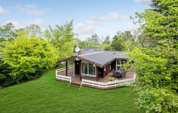 Escape to a serene cabin surrounded by lush greenery, featuring a spacious deck and a cozy covered seating area.
