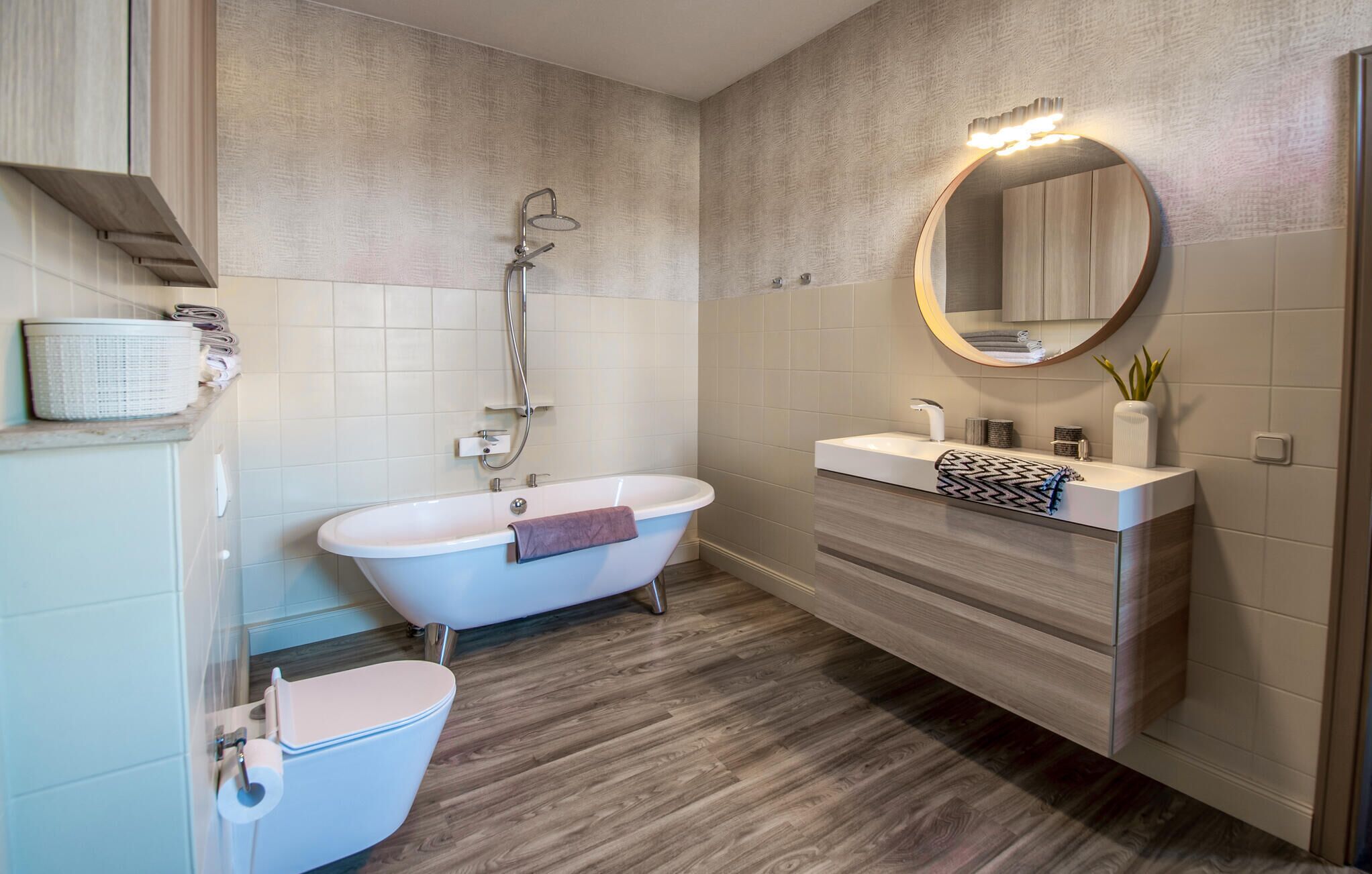 A modern bathroom with a freestanding bathtub, a toilet, a vanity with a mirror, and a shower.