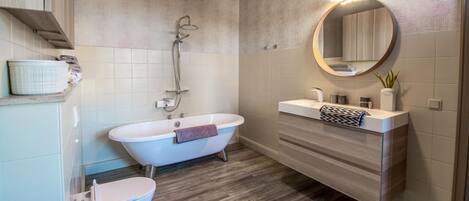 A modern bathroom with a freestanding bathtub, a toilet, a vanity with a mirror, and a shower.