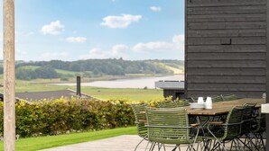 An outdoor dining area with a view of a lake and hills.