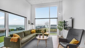 A modern living room with a green sofa, a grey armchair, and a round coffee table.