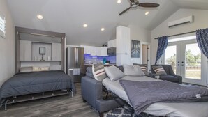 Une chambre à coucher moderne et compacte, dotée d’un grand lit, d’un canapé-lit et d’un espace bureau.