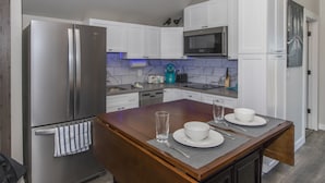 Une cuisine moderne avec des meubles blancs, des appareils en acier inoxydable et un îlot central en bois aménagé en coin repas.