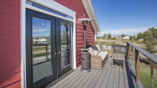 Une terrasse avec un canapé en osier, une table et une poubelle.