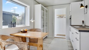 Een moderne keuken met een houten tafel, rieten stoelen en een wit kastje.