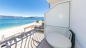 Un balcone con vista sulla spiaggia e sul mare, un water bianco e una ringhiera in metallo.