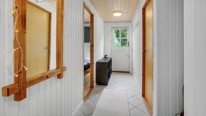 A hallway with wooden doors, a small table, and a window with a view of greenery.