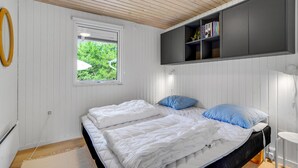 A bedroom with a bed, a window, a bookshelf, and a desk.