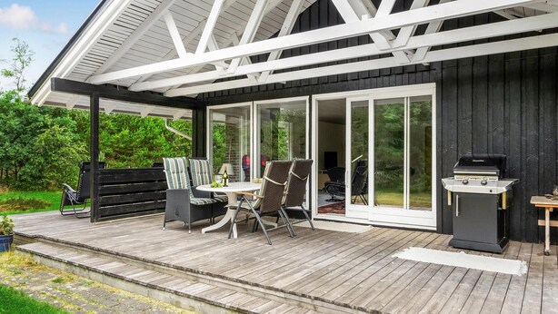 A deck with outdoor furniture, a grill, and a sliding glass door leading to a patio area.