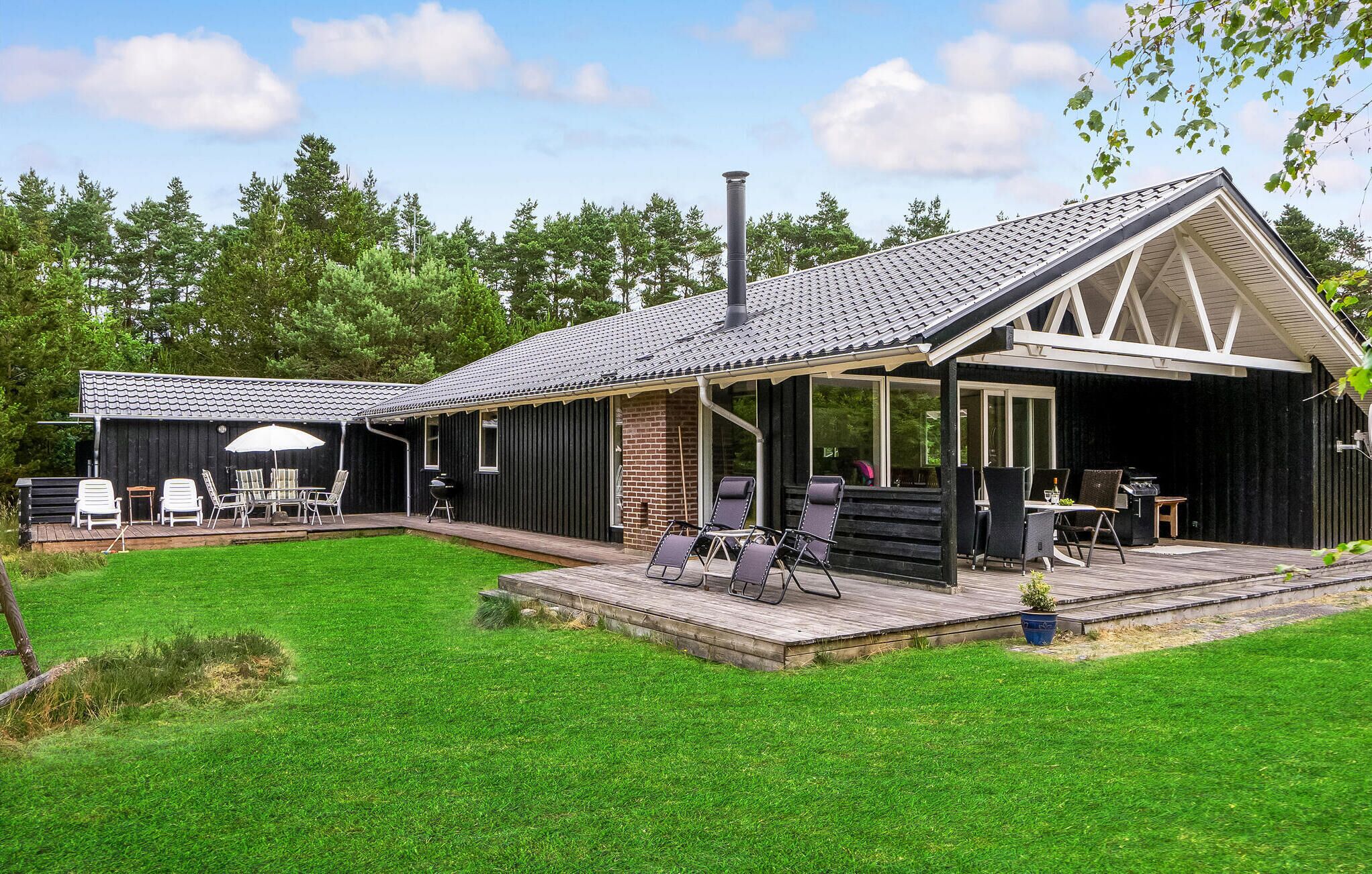 A modern house with a covered patio, outdoor seating, and a barbecue area.