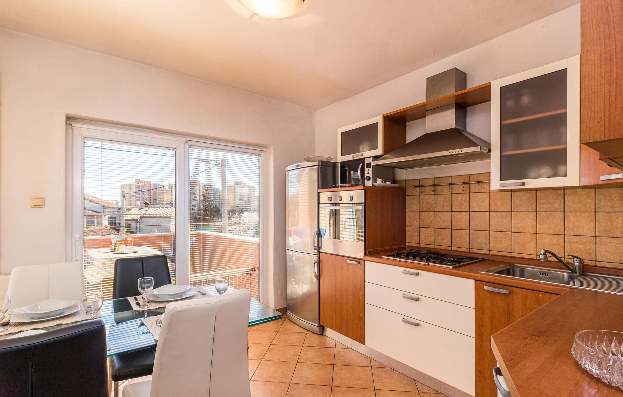 Cocina compacta con refrigerador, estufa, microondas y gabinetes de madera.