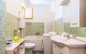 A compact bathroom with a toilet, sink, and shower.