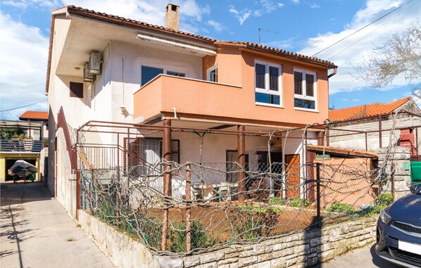 A two-story house with a balcony, a garage, and a stone wall.