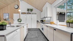 A modern kitchen with white cabinetry, a built-in oven, a microwave, and a large window providing natural light.