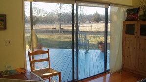 Une pièce dotée d’une terrasse en bois, d’une porte-fenêtre coulissante donnant sur un espace extérieur, d’une chaise en bois et d’un meuble.