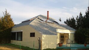Une maison de plain-pied avec un toit en pente, une cheminée et une porte d’entrée.
