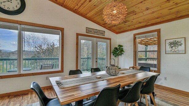 Un espace repas avec une table en bois, des chaises noires et un luminaire suspendu.