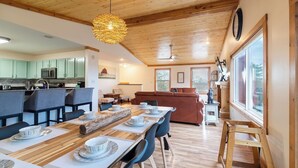 Une cuisine moderne avec un coin repas, un plafond en bois et de grandes fenêtres.