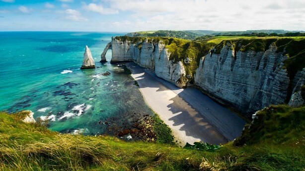 Eine Küstenlandschaft mit Klippen, einem Strand und freiem Blick auf den Ozean.