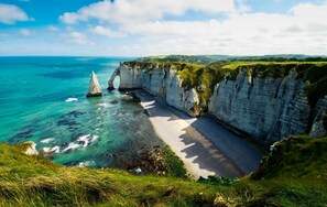 Paisagem costeira com falésias, uma praia e uma vista clara do oceano.