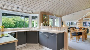 Een moderne keuken met een groot raam, donkere kasten en een eethoek met houten meubels.
