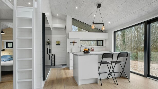 Cozinha moderna com ilha central, dois banquetes e uma grande janela com vista para o exterior.