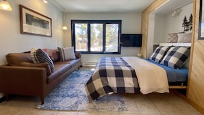A bedroom with a bed, a sofa, a television, and a window with a view of trees. - Cozy Ski-In / Walk-Out @ 4 O'Clock Lodge (Breckenridge)