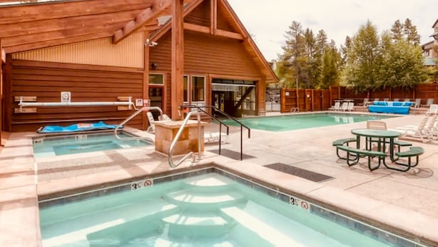 A wooden building with a pool area, including a hot tub, lounge chairs, and a table. - Cozy Ski-In / Walk-Out @ 4 O'Clock Lodge (Breckenridge)