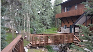 A wooden deck with a stone pathway leading to a building with a wooden exterior and a balcony. - Cozy Ski-In / Walk-Out @ 4 O'Clock Lodge (Breckenridge)