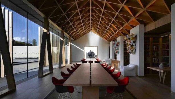 A long conference table with red chairs, large windows, and a geometric ceiling design. - Refurbished Coach House in rural setting. (Waddesdon)