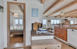 A spacious kitchen with wooden beams, a large window, and a dining area with a bench. - Lovely apartment in Skårup Fyn with WiFi (Skårup Fyn)