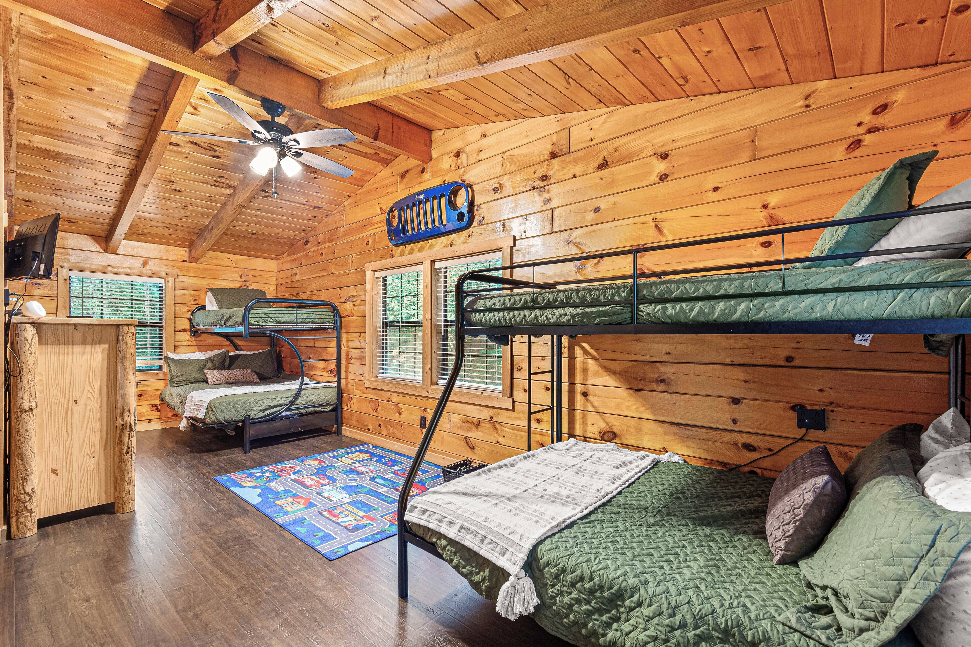A cabin with a bunk bed, a desk, and a ceiling fan.