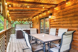 A wooden deck with a table and chairs, a hot tub, and a covered area with a door. - Private, Hot Tub, Game Room, Wi-Fi, Pigeon Forge (Sevierville)