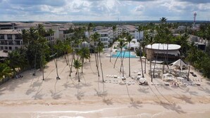 Un resort con piscina, palmeras y acceso a la playa.