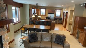 A spacious living area with a leather sofa, a wooden coffee table, and a kitchen in the background.