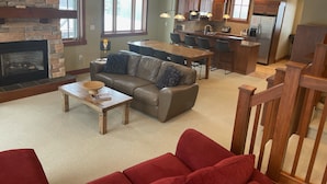 A spacious living area with a fireplace, a dining table, and a kitchen in the background.