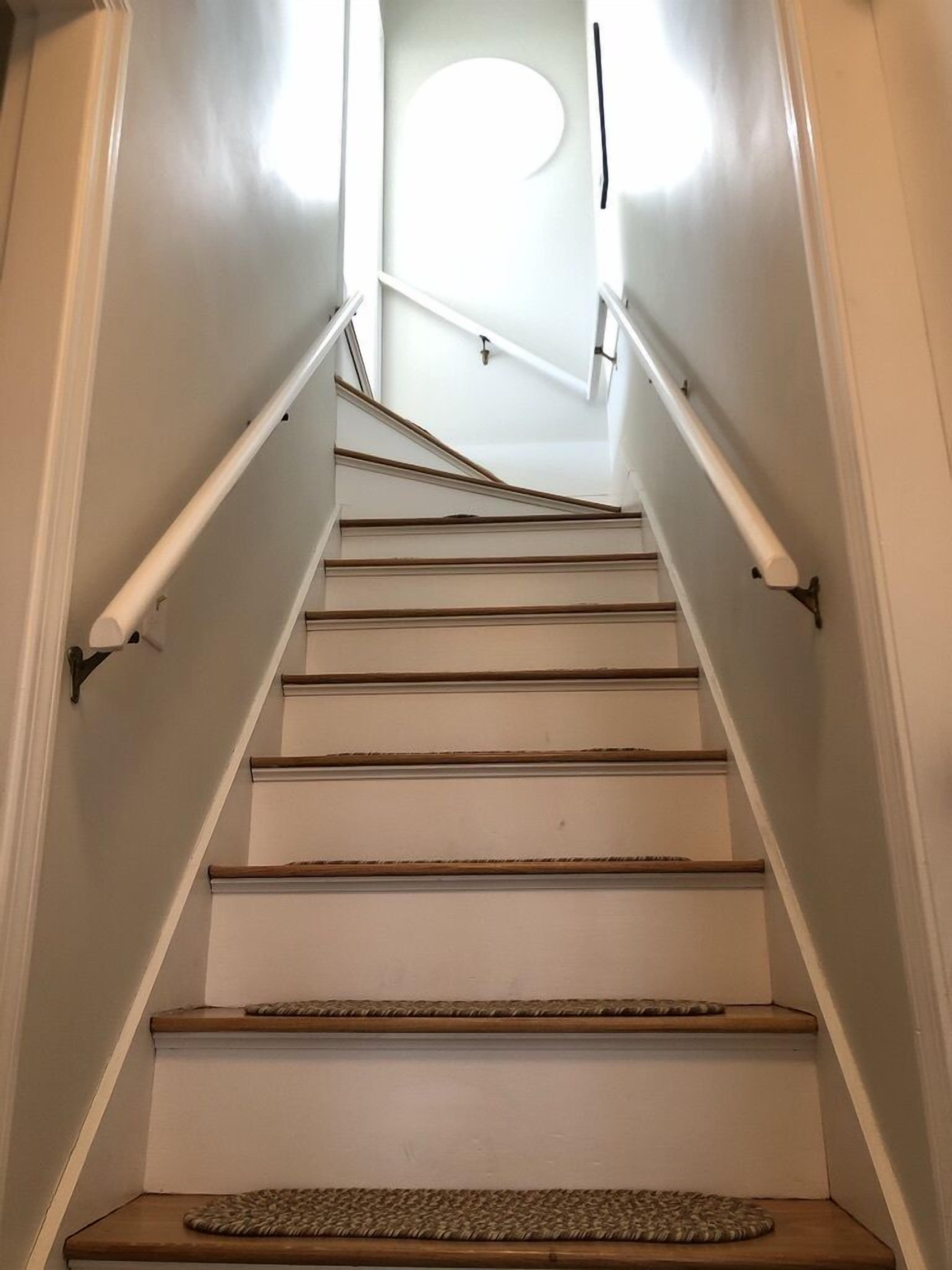 A staircase with white walls and wooden steps.