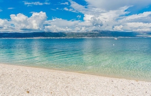 A beach with clear turquoise water, a sandy shore, and distant mountains under a partly cloudy sky. - 1 bedroom lovely apartment in Slatine (Slatine)