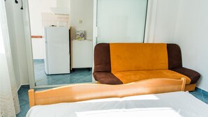 Ein Zimmer mit einem Bett, einer Couch, einem Kühlschrank und einem Fenster.
