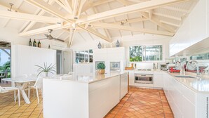 A spacious kitchen with white cabinetry, a large island, and a tiled floor.