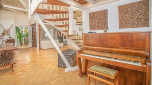 A spacious living area with a grand piano, a staircase, and decorative wall art.