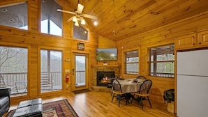 A wooden cabin interior with a dining area, fireplace, and large windows. - Free Dollywood Tix+MtnViews+Pool+Couples+DogsOK (Sevierville)