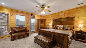 A log cabin-style bedroom with a large bed, a leather couch, and a ceiling fan. - Free Dollywood Tix+MtnViews+Pool+Couples+DogsOK (Sevierville)