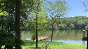 Un cadre paisible au bord d’un lac, avec un quai, une végétation luxuriante et un ciel dégagé.