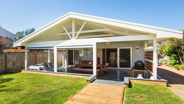 Een modern huis met een overdekte patio, een eethoek en een garage.