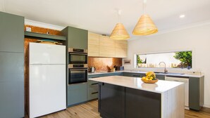 Een moderne keuken met een centraal eiland, ingebouwde apparatuur en hanglampen.