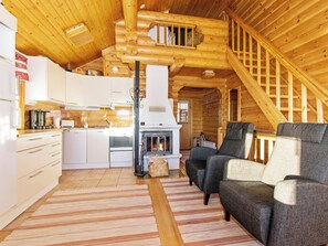 L’intérieur d’une cabane en rondins comprend une cuisine, un espace de vie et un escalier.