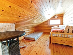 Ein gemütliches Blockhaus mit Holzvertäfelung, einem Bett mit Kissen, einem kleinen Tisch und einem Fenster.